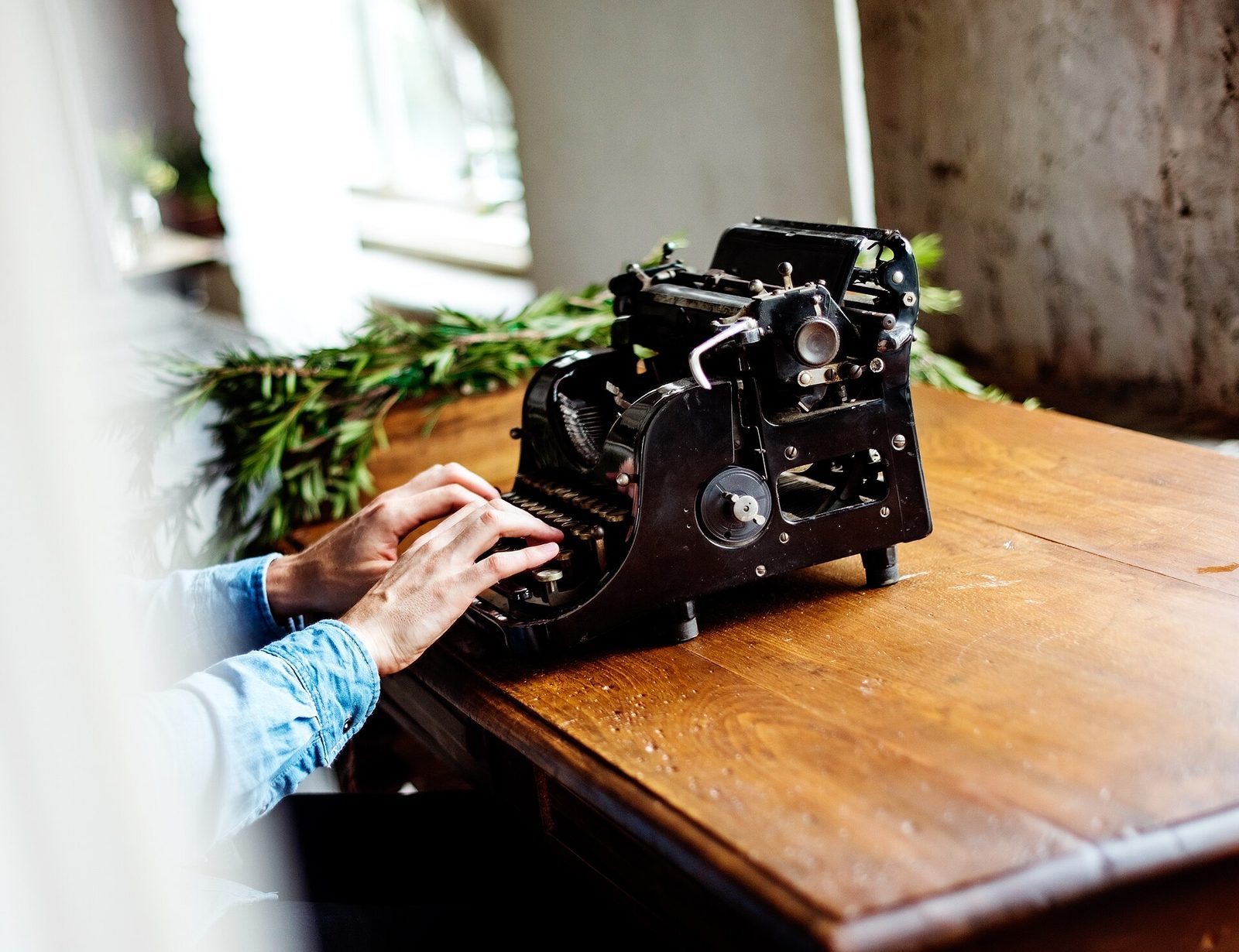 vintage manual typewriter resting upon an author wooden writing desk viewed in quiet library light